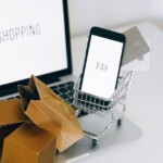 a miniature shopping cart and smartphone on macbook laptop shopping deals