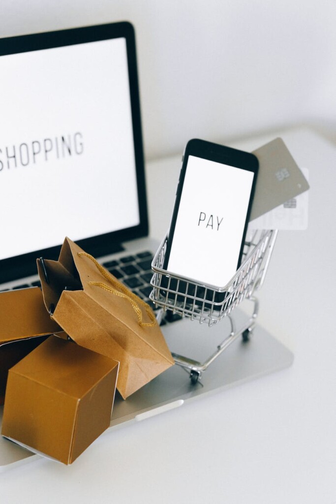 a miniature shopping cart and smartphone on macbook laptop online shopping for Black Friday