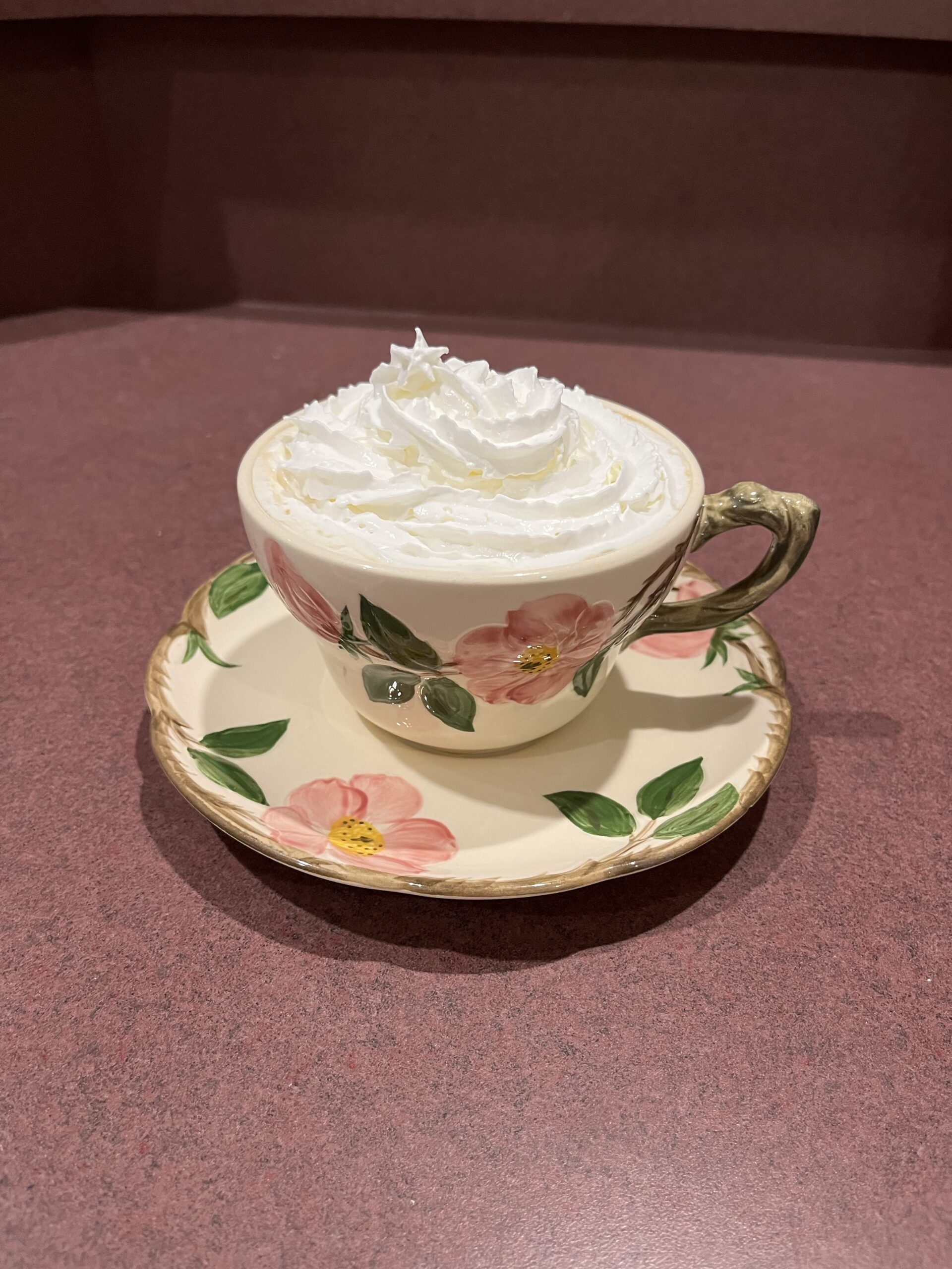 coffee with cream and sugar in cup and saucer topped with spray whipped cream
