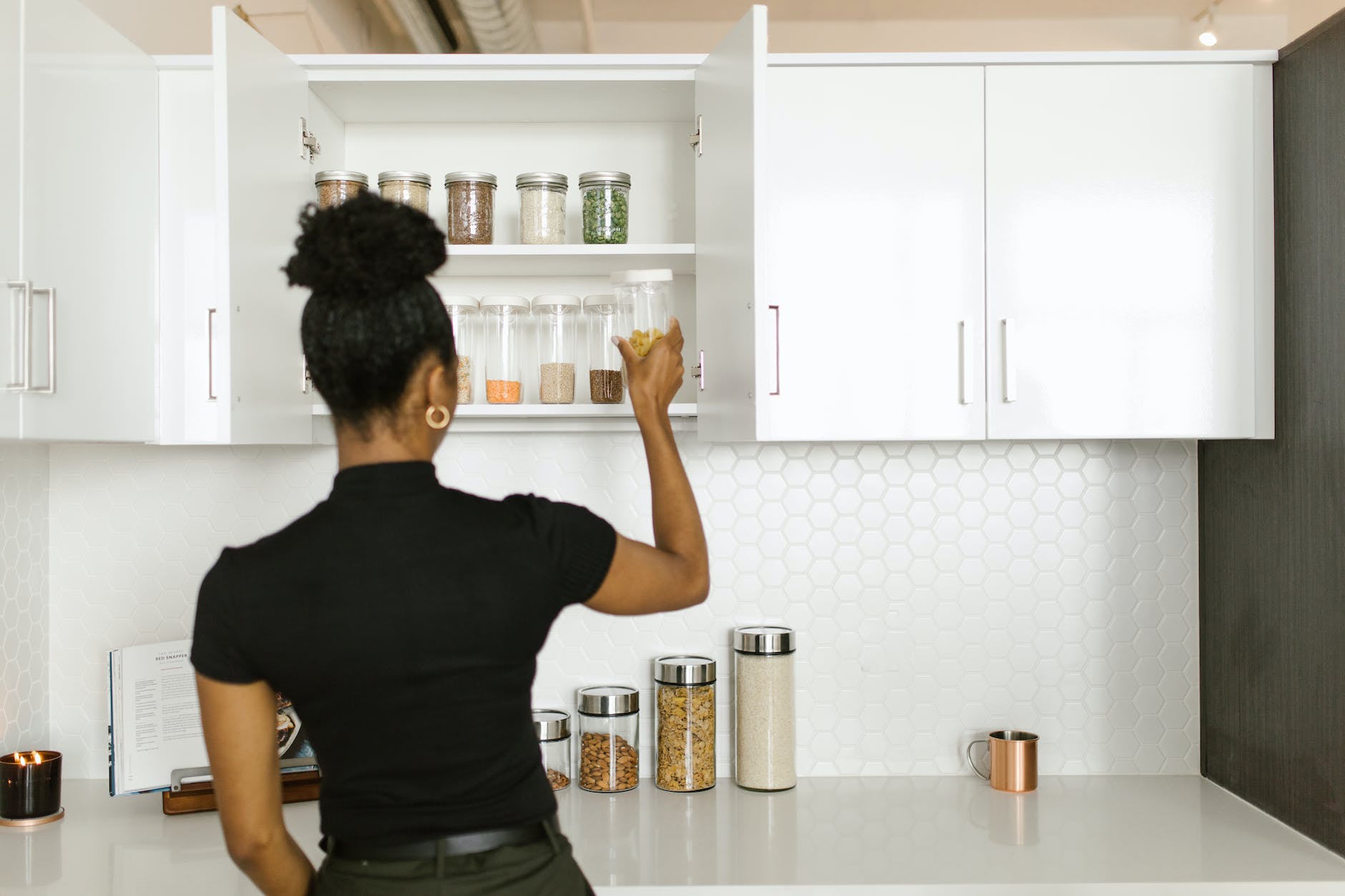 woman putting glass containers on a kitchen cabinet declutter your home