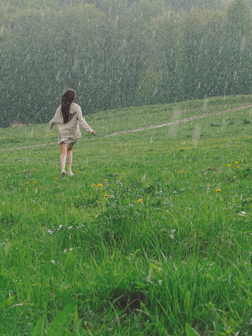 woman enjoying the rain outside a grass field showers of blessings