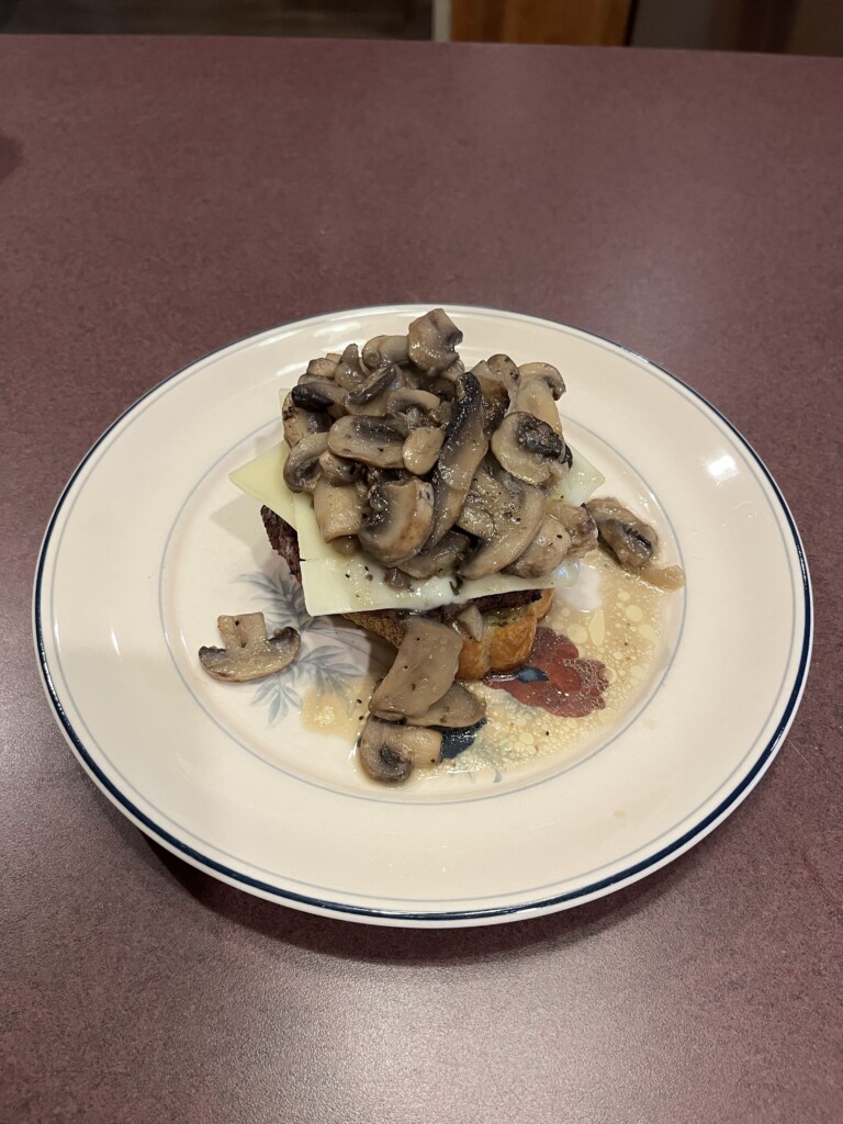 hamburger patty on Texas toast topped with Swiss cheese and mushrooms