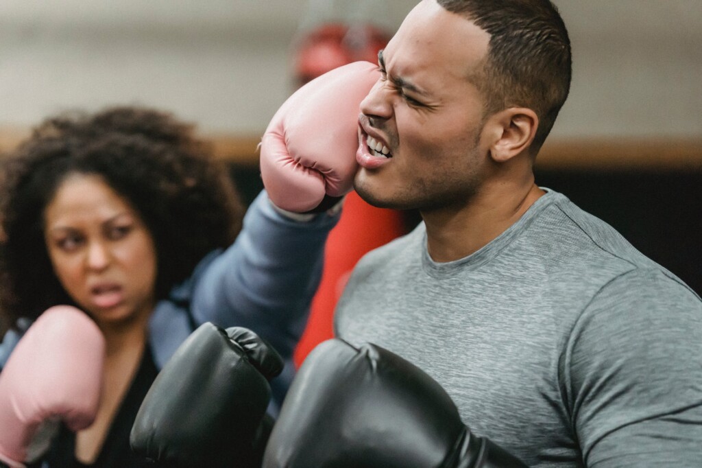 motivated young black woman punching face of ethnic male couch during training