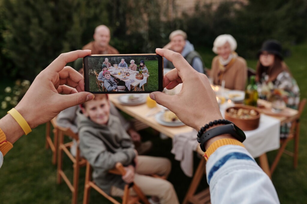 unrecognizable person taking photo of family dinner on smartphone