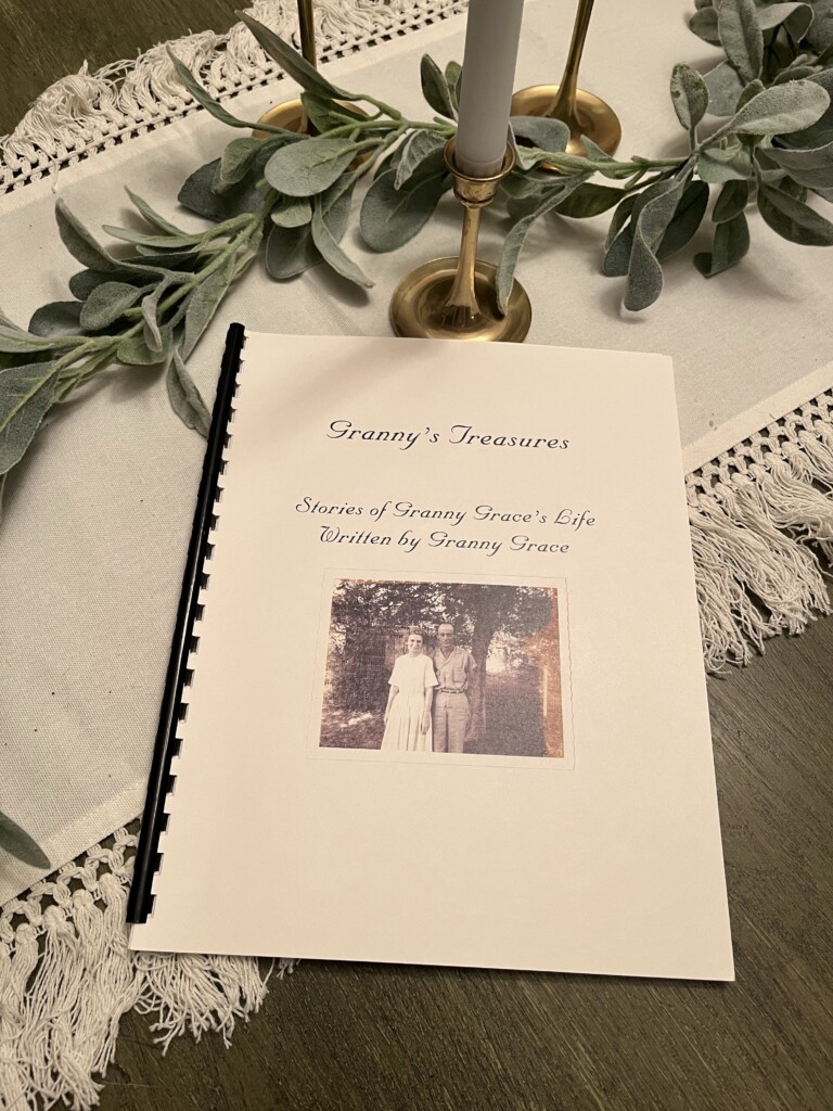 A spiral-bound book titled "Granny's Treasures: Preserving Granny Grace's Legacy," resting on a table with decorative leaves and candlesticks.