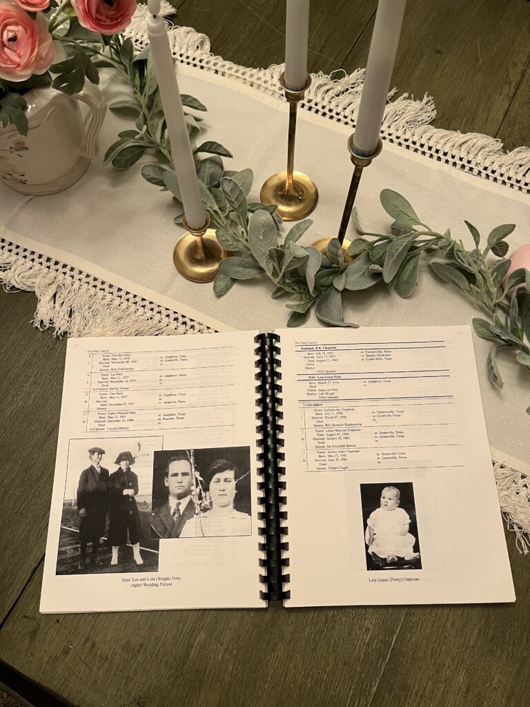 Open family history scrapbook on a wooden table, illustrating how to preserve and pass down your family history through old photographs and genealogical documents, flanked by candles and a floral arrangement.